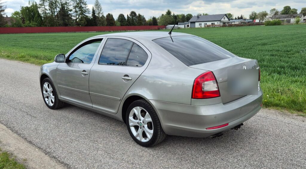 Srebrna Skoda Octavia sedan z rozmytą tablicą rejestracyjną na wiejskiej drodze
