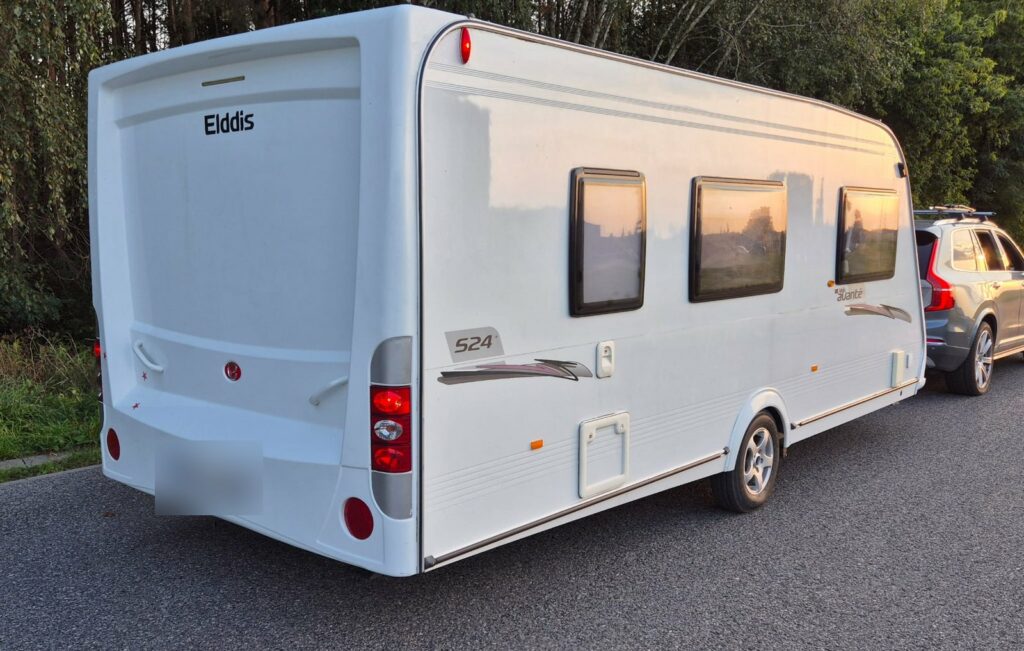 Przyczepa kempingowa Elddis Avante holowana przez SUV-a na drodze o zachodzie słońca