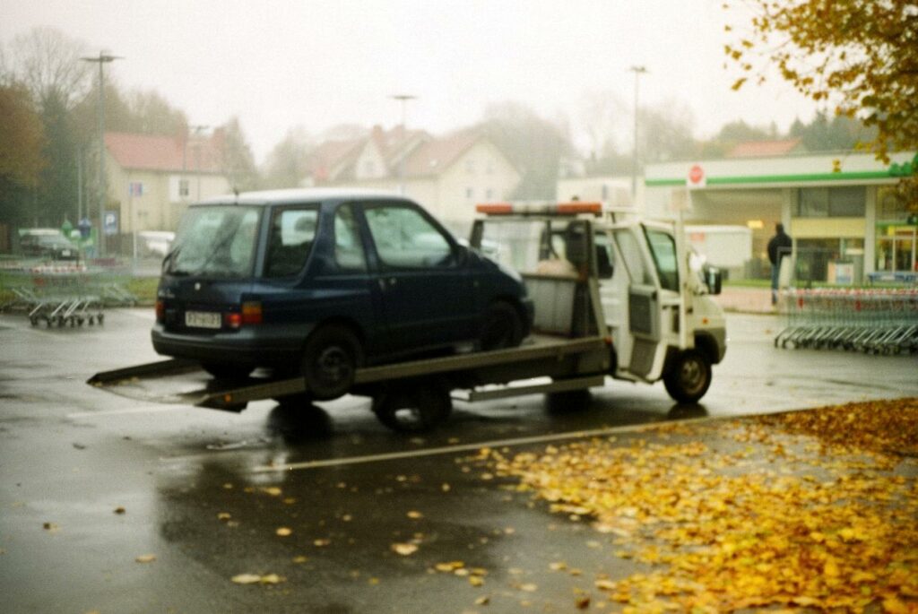 Granatowy kompakt na lawecie na mokrym parkingu przy markecie w pochmurny jesienny dzień