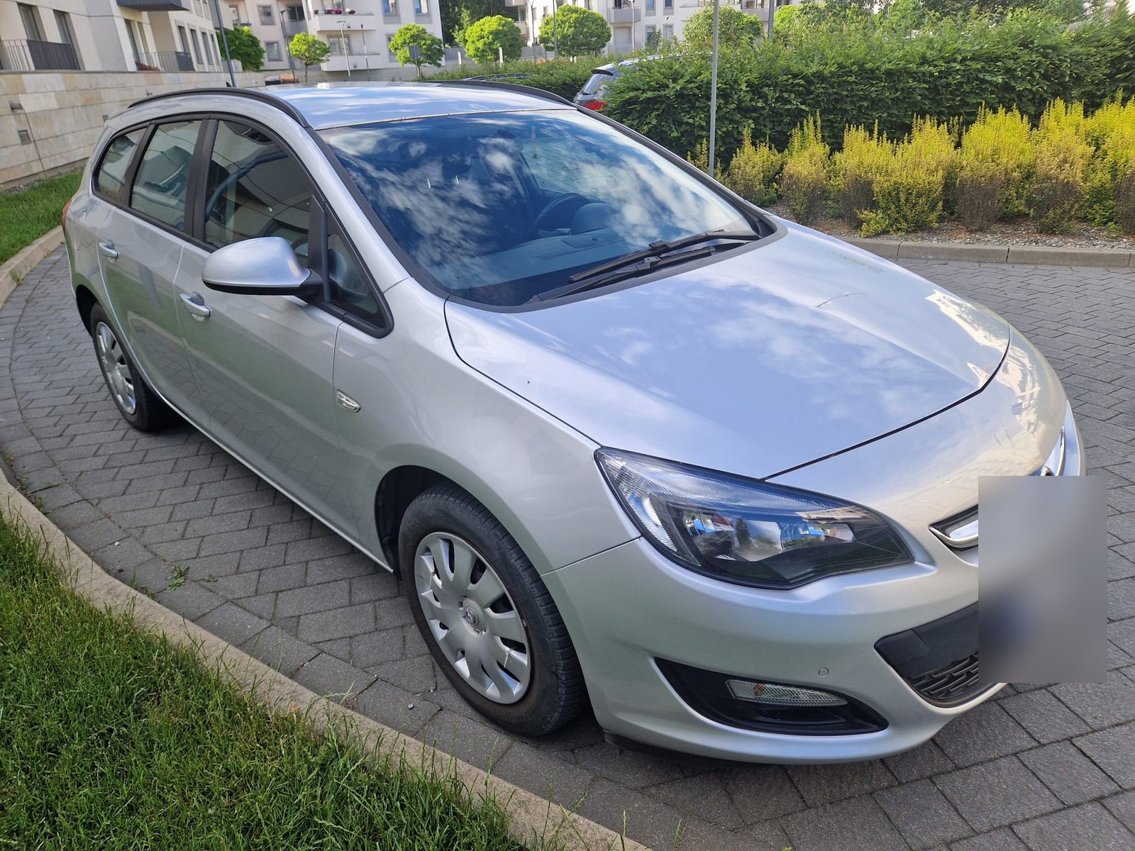 Srebrny Opel Astra kombi na osiedlowym parkingu przed sprzedażą handlarzowi